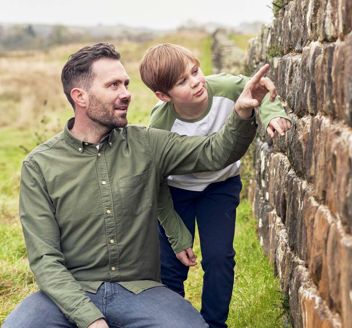 Image: A parent and child examine Hadrian's Wall