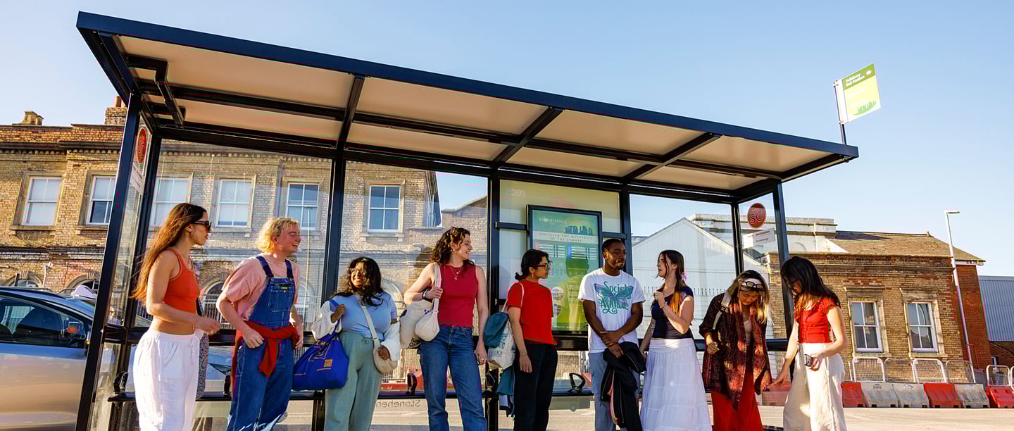 A group of people stood at a bus stop at Salisbury Bus Station.