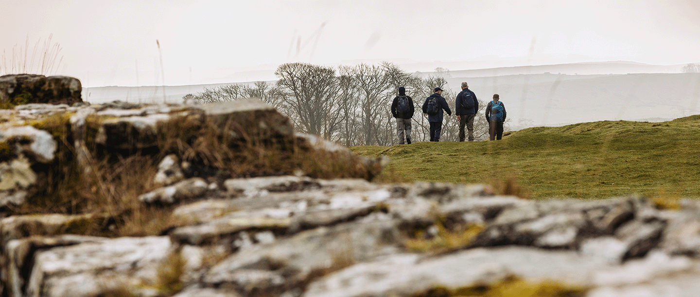 Photo of four people in the distance walking along Hadrian's Wall in winter