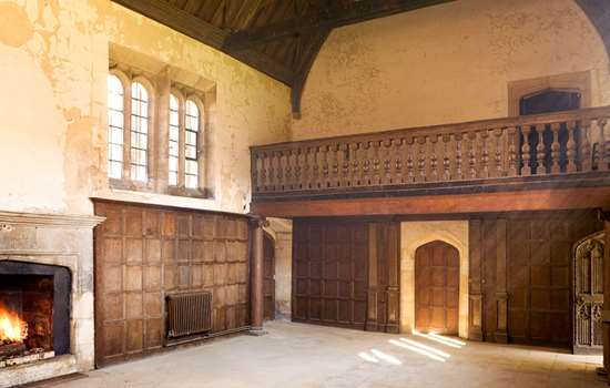 Interior view of room with fireplace, wood panelled walls and gallery at Apethorpe Palace