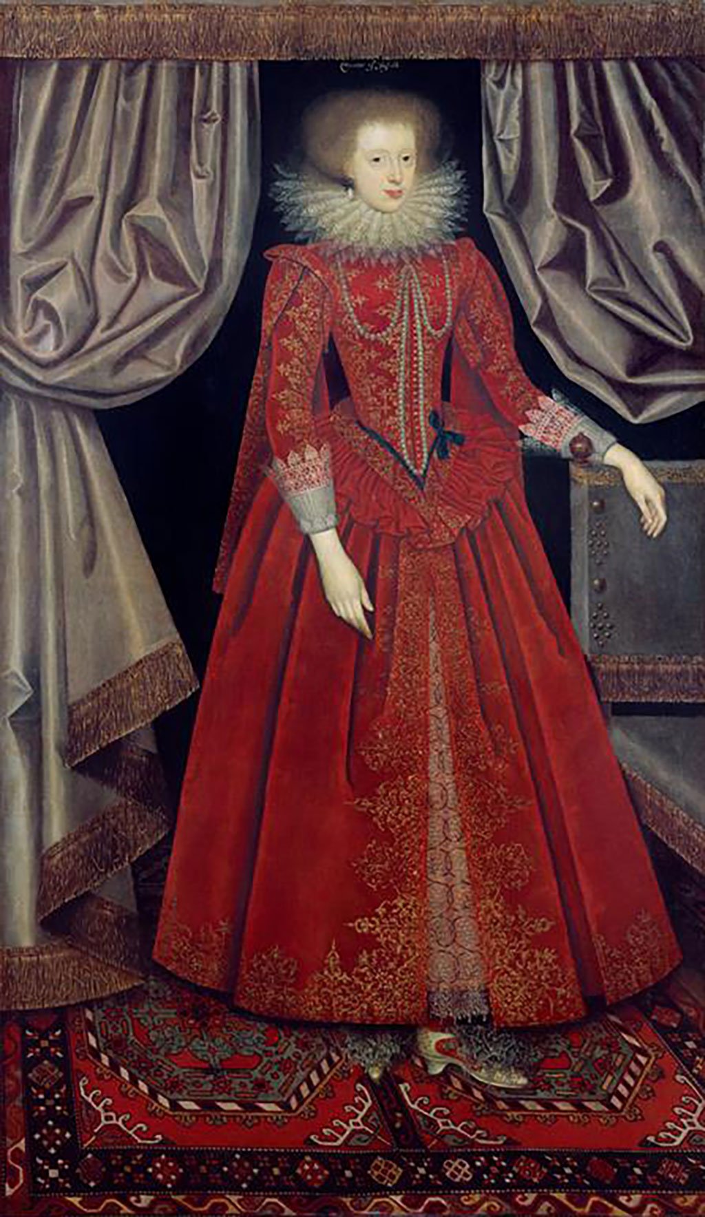 Colour portrait of a pale skinned woman with frizzy hair in a long red dress with lace cuffs, pearl details, and gold embroidery, a pearl earring, and a large lace neck ruff