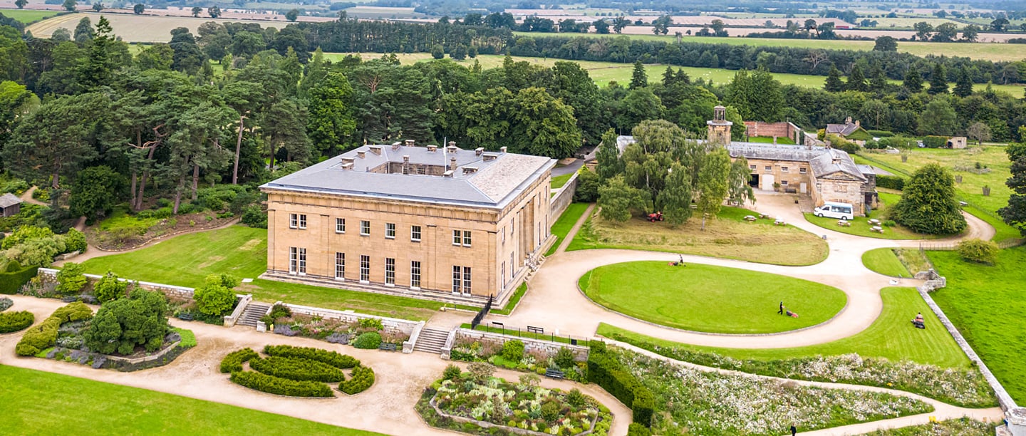 A high angle view of Belsay Hall and the surrounding manicured gardens.