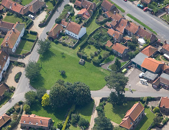 An aerial view of the village of Binham, showing the market cross at the centre of the village green