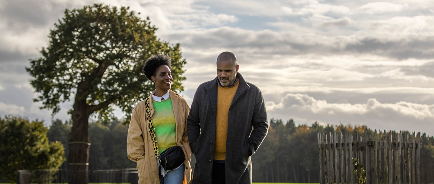 Image: a couple walk in front of the Royal Oak