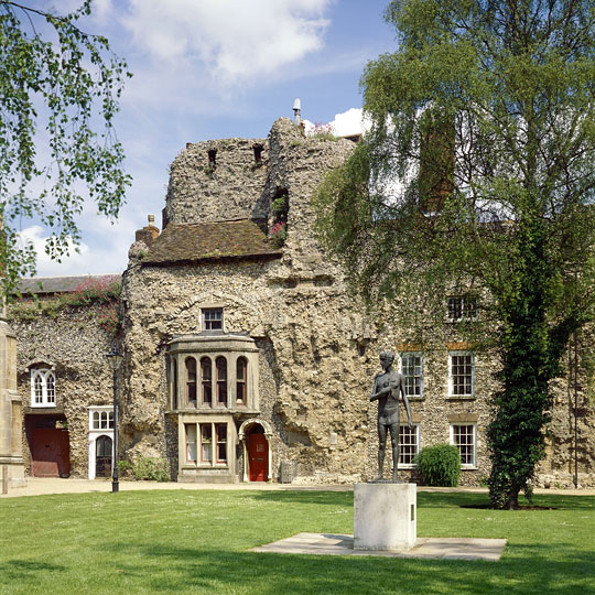Post-medieval houses built into the semi-ruined west front, with a statue of St Edmund in the foreground on the lawn