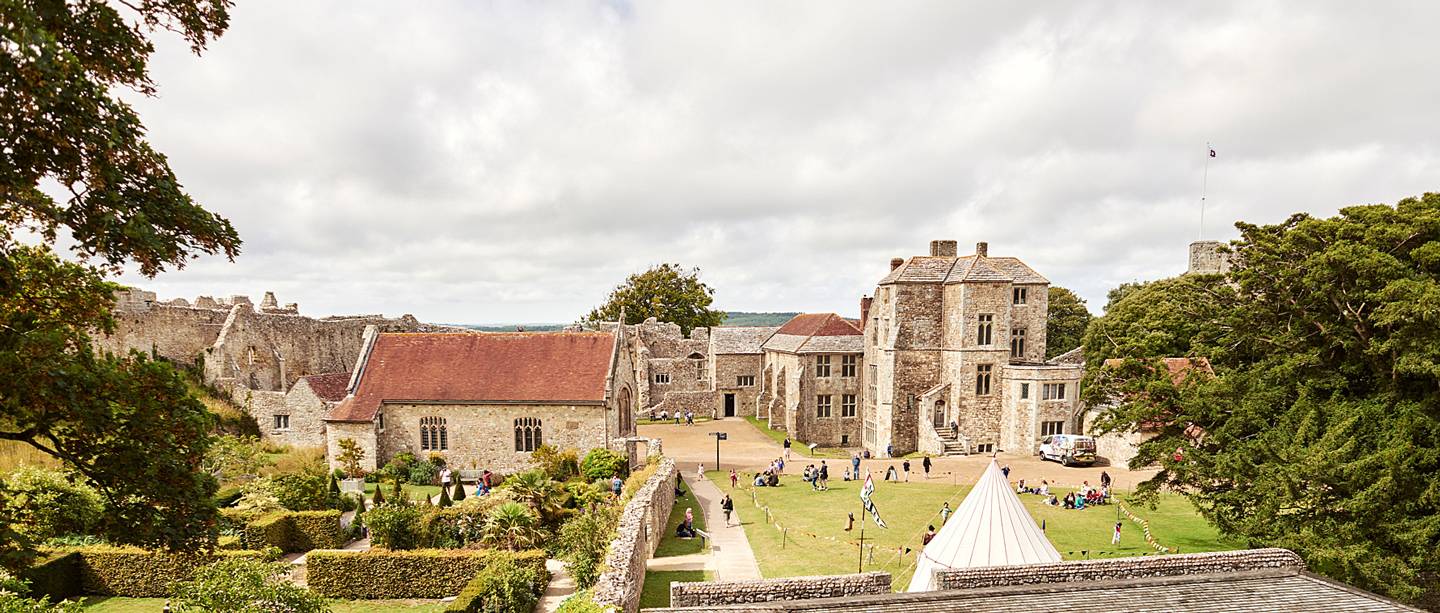 A view of Carisbrooke Castle and the Church with a restored roof from a high angle. There are people waking around the castle grounds.