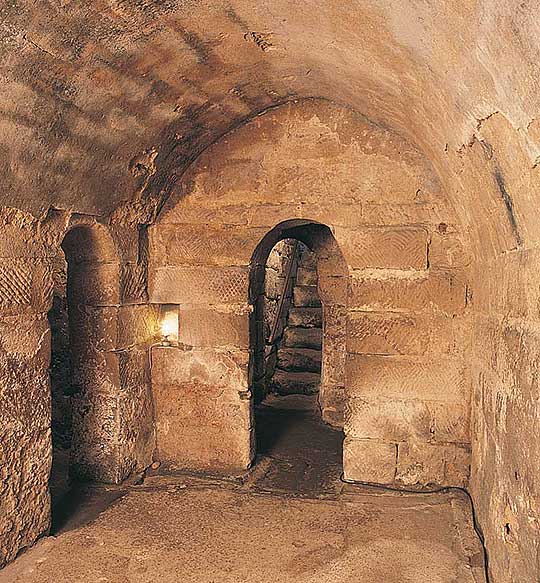 Interior of Hexham crypt with view through narrow arched doorway to steps leading up Interior of Hexham crypt with view through narrow arched doorway to steps leading up
