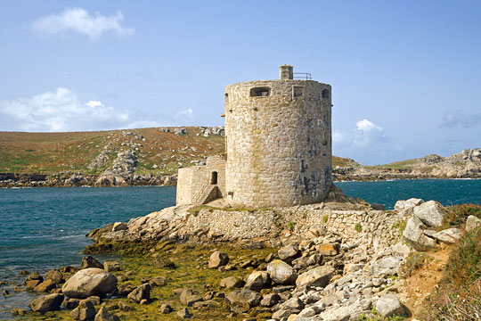 Cromwell’s Castle set on the rocky shore of Tresco with the sea and Bryher beyond