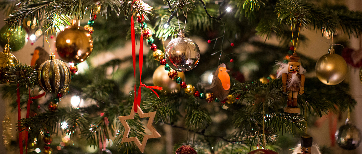 A close up of a decorated Christmas tree with fairy lights and baubles.