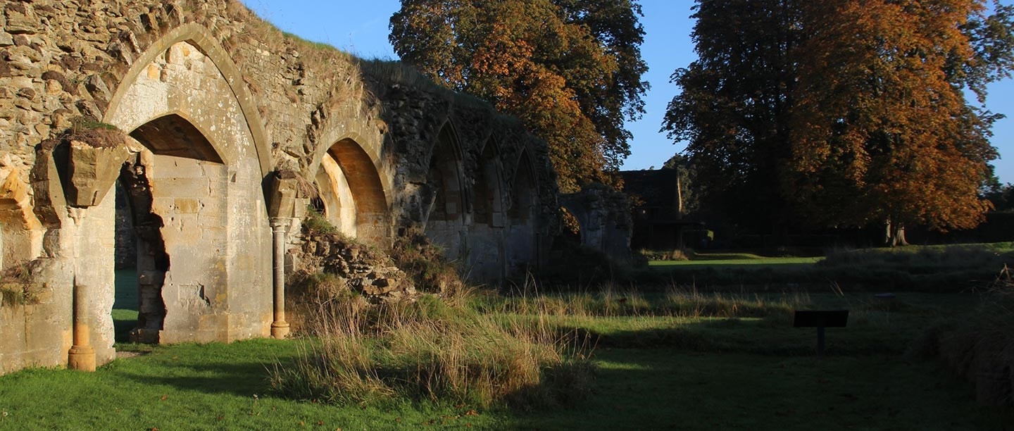 Photograph of Hailes Abbey ruins in early morning sunlight set within autumnal Cotswolds landscape