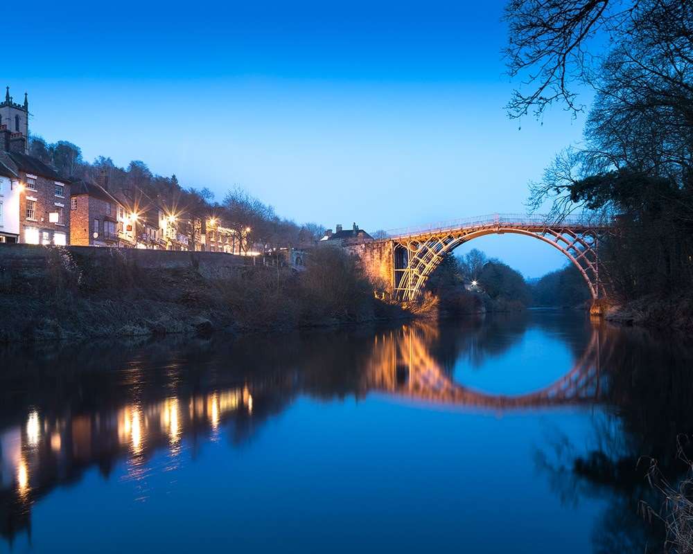 The Iron Bridge lit up against a blue nighttime sky