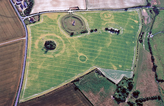 An aerial photograph of Knowlton earthworks seen from the north-east, showing the henge and church as well as crop marks of many ploughed out buried features