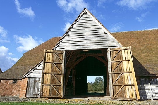 Leigh Court Barn, one of the earliest surviving cruck barns in Britain, its huge wooden double doors standing open