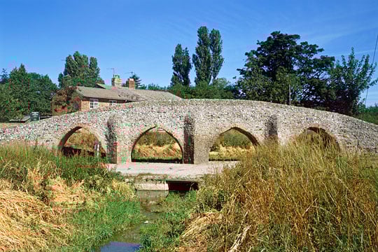 The 15th century bridge from the south with stream in foreground and cottage behind The 15th century bridge from the south with stream in foreground and cottage behind