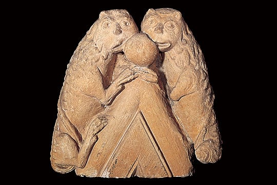 Stone sculpture of two lions grasping the top of a small gable from the cathedral at Old Sarum