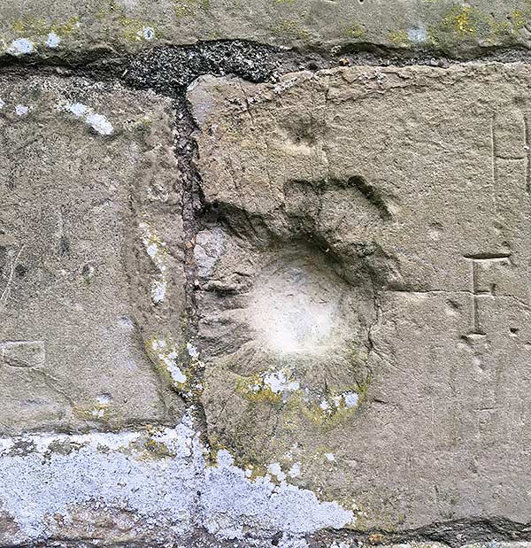 Damage to the castle wall near the main entrance, which may have been caused by enemy fire