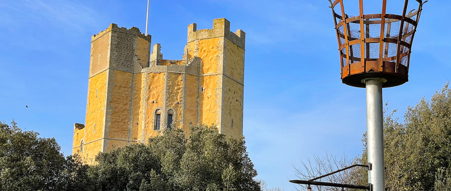 A low angle view of Orford Castle under a blue sky.