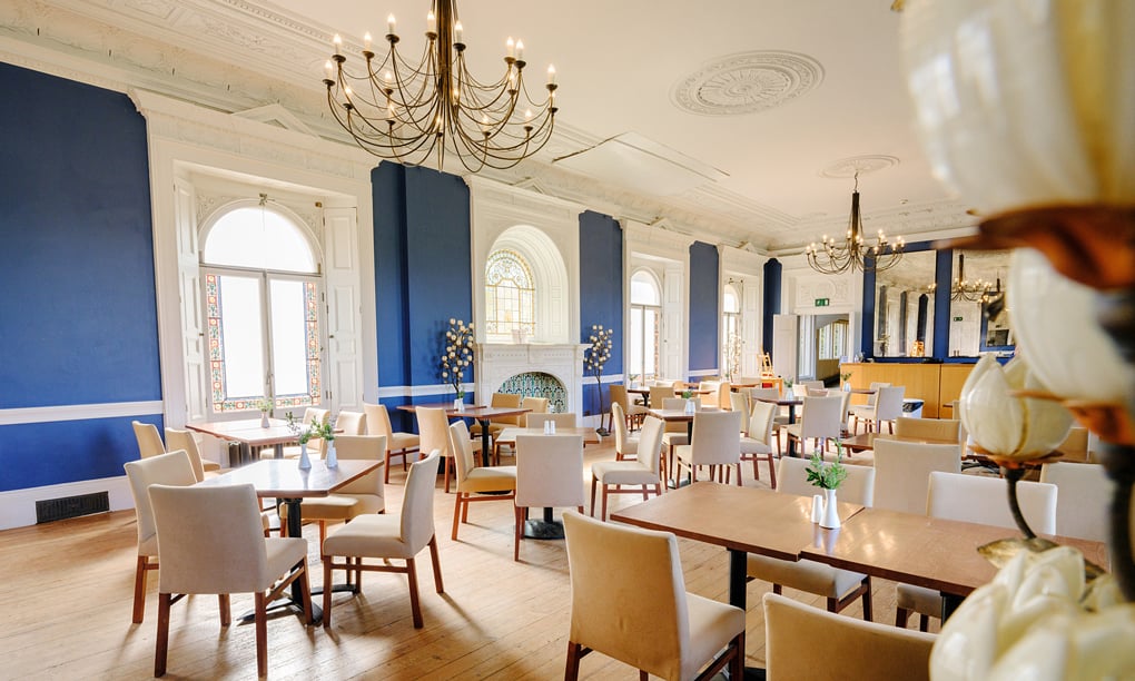 The Victoria Hall Restaurant at Osborne with painted blue walls and chandeliers. 