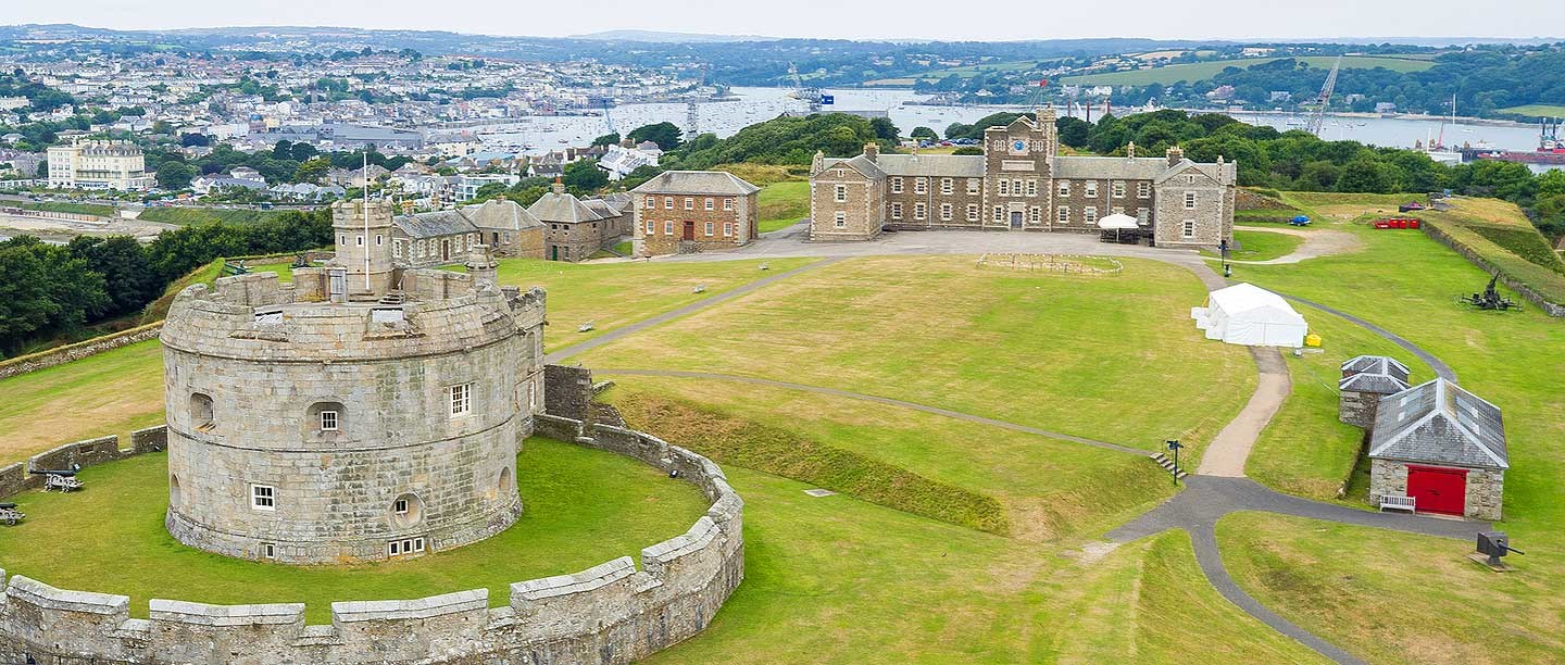 A view of the castle from above showing a grassy area and grey castle and walls.
