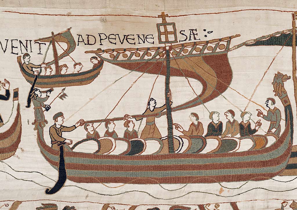 A large ship loaded with men and horses depicted in the Bayeux Tapestry, with a smaller ship upper left. The device on the masthead of this ship, possibly a papal banner or a lantern, suggests that it is probably the Mora, the ship paid for by Duke William’s wife, Matilda