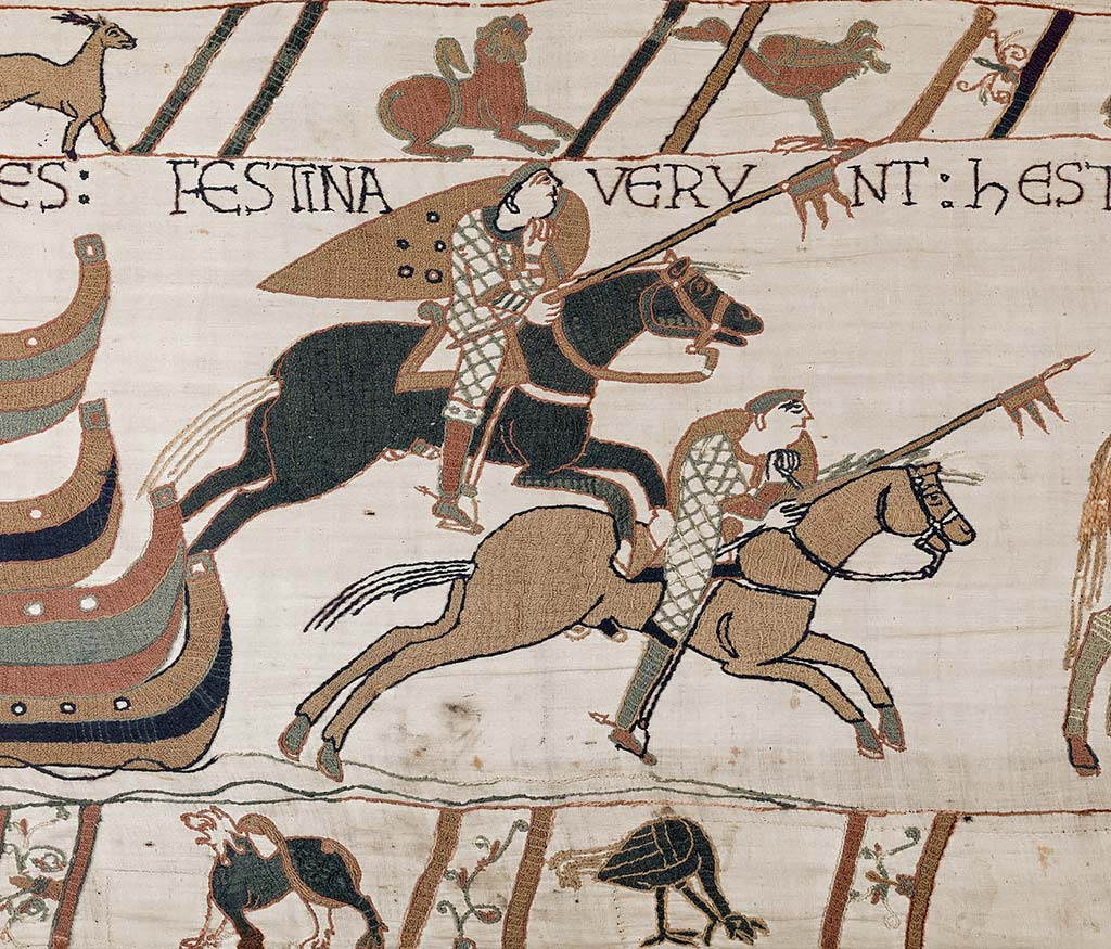 A scene from the Bayeux Tapestry depicting two scouts galloping away from ships on the left. The Latin caption tells us that they are hurrying towards Hastings to seize food