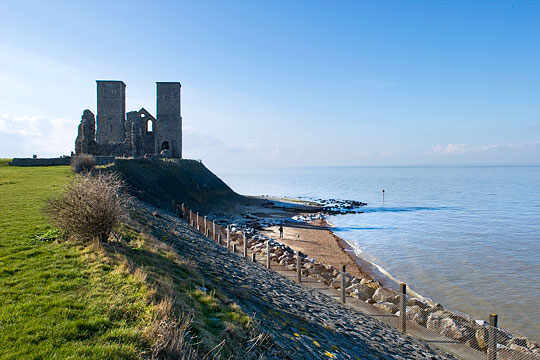 A view of the imposing towers of the medieval church at Reculver, standing on the edge of a low cliff above the rocky shore A view of the imposing towers of the medieval church at Reculver, standing on the edge of a low cliff above the rocky shore