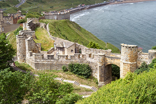 View of the barbican bridge, gatehouse and barbican at Scarborough Castle with the bay below and the waves rolling in