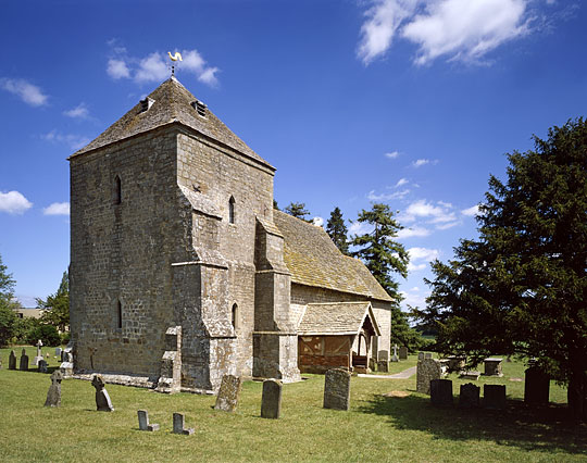 St Marys, Kempley, in full sunshine with grave head stones in foreground St Marys, Kempley, in full sunshine with grave head stones in foreground