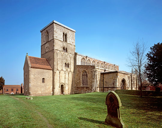 The Saxon tower of St Peter's Church Barton-Upon-Humber, with its distinctive decoration of stone strips and a single grave headstone in the foreground