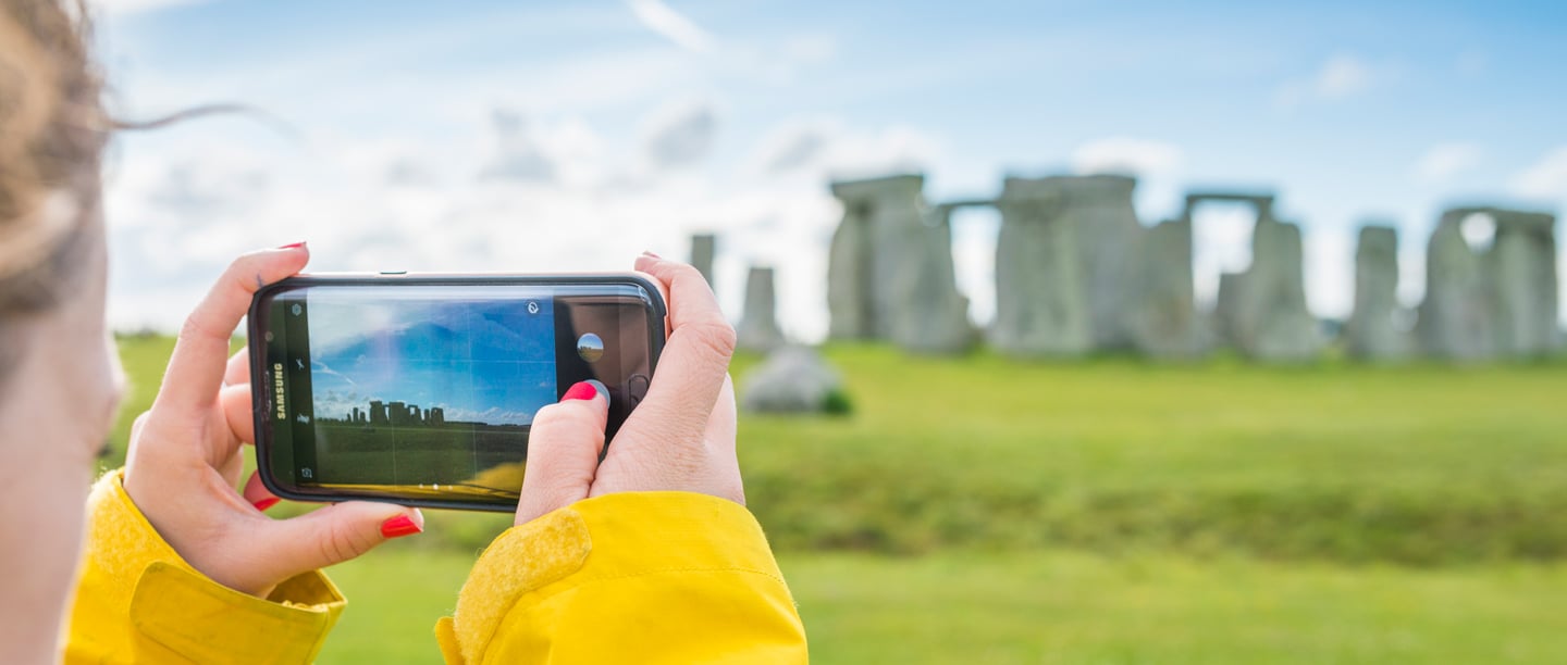 Someone takes a landscape photo on a mobile phone of Stonehenge.