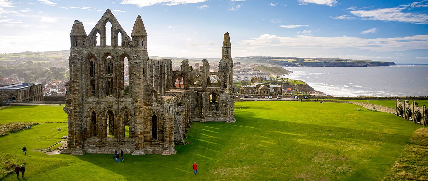 An aerial view of Whitby Abbey ruins with the town and coast in the background
