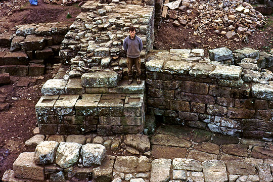 The abutment of the rebuilt Wall-bridge under excavation in 1984–5, with an archaeologist standing on the stonework to give scale to the massive walls
