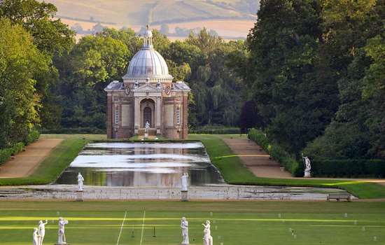 View across the lawns and water to the domed Archer Pavilion at Wrest Park
