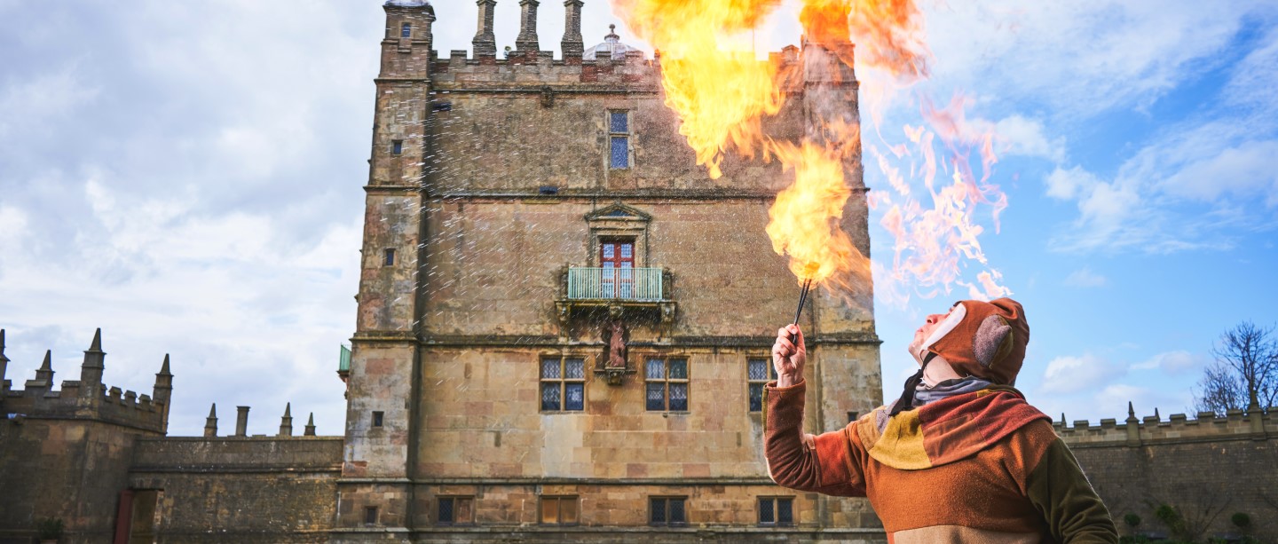 Image: A jester breathing fire in front of Bolsover Castle