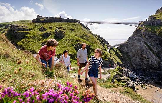 Image: family exploring with Tintagel Castle behind