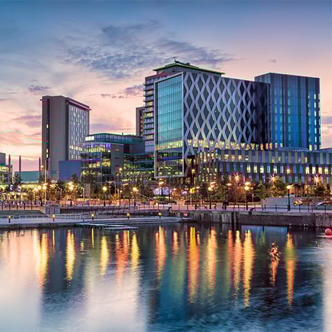 Large modern buildings viewed across water at sunset
