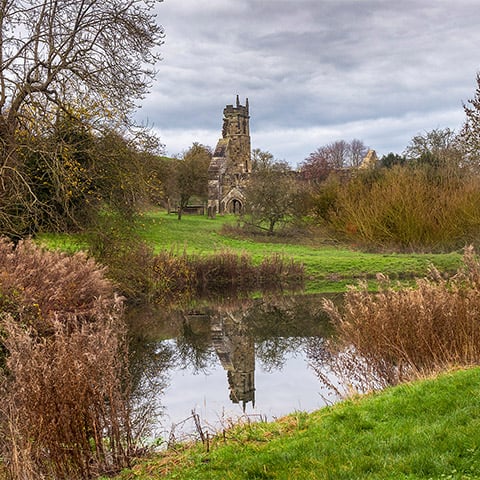 The ruined church at Wharram Percy seen the other side of a pond