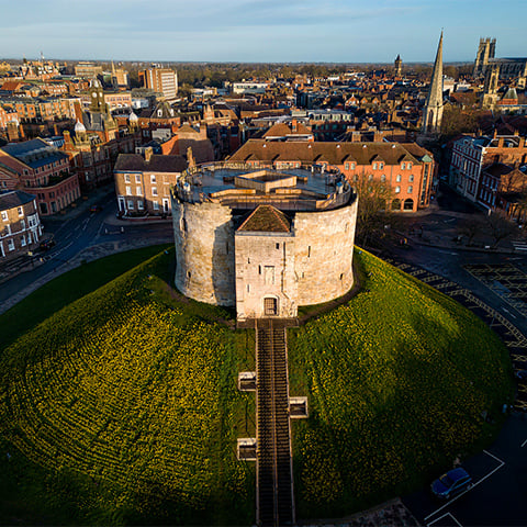 A squat tower (Clifford's Tower) sits on a large grass mound
