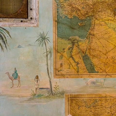Close up of a wall featuring an image of a camel and some maps