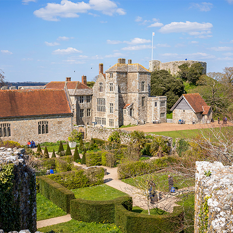 A small church with large buildings beyond surrounded by castle walls (Carisbrooke Castle)