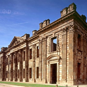 A side view of the ruins of Sutton Scarsdale Hall underneath a blue sky.