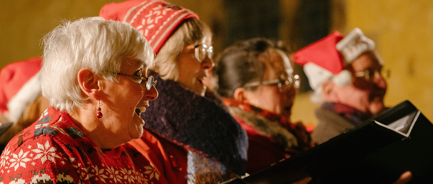 Photo of a group of people wearing Christmas clothes singing carols at Bolsover Castle