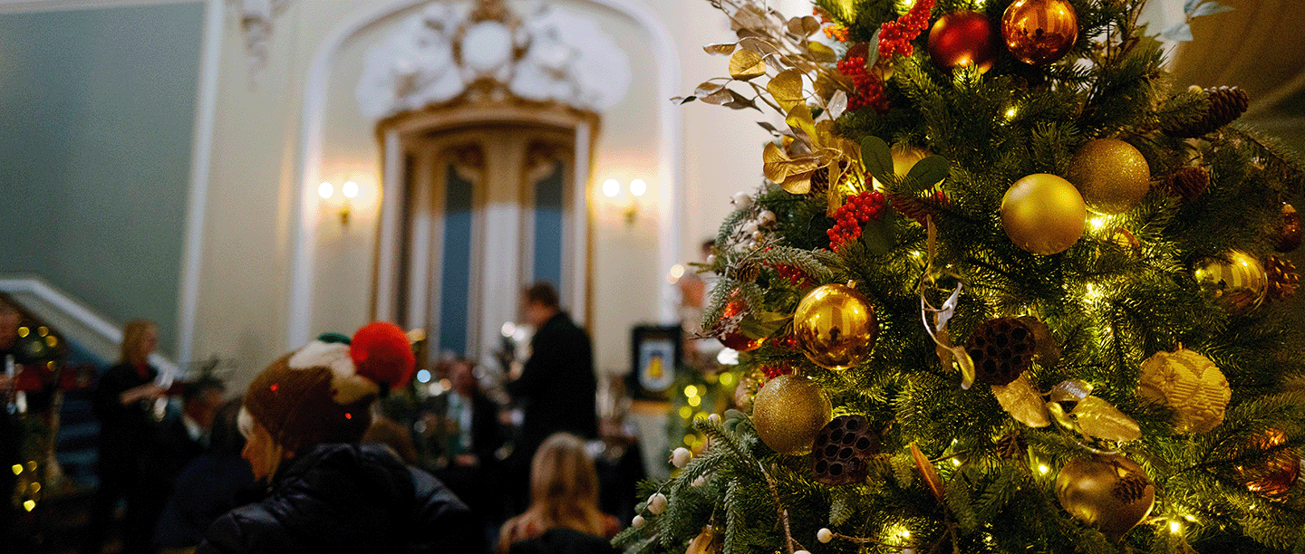 Photo of a decorated Christmas tree at Wrest Park with visitors gathered next to it