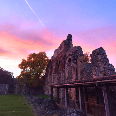 Ruins of St Augustine's Abbey under a colourful pink and blue sunset.