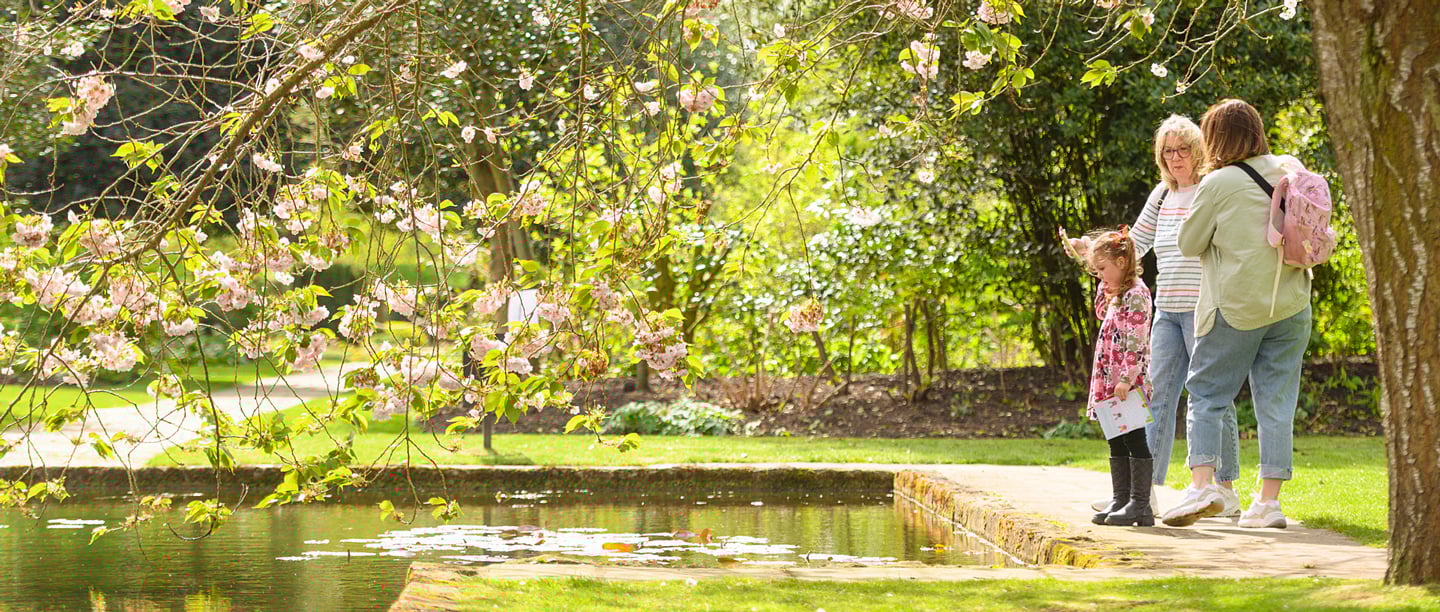 Two women and a young girl stand by the moat at Eltham Palace.