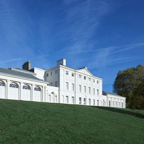 An exterior side on view of Kenwood House underneath a blue sky.