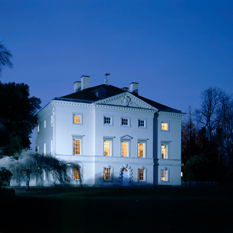 The exterior of Marble Hill at night with several interior room lights on. 