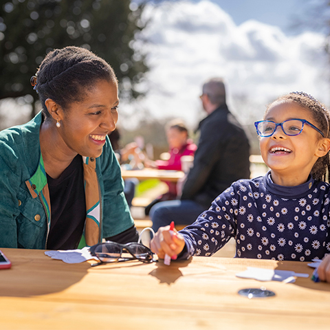 A woman and a young girl sit at a table laughing