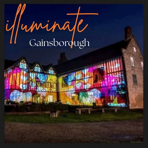 A view of the exterior of Gainsborough Old Hall lit up with colourful projections at night.