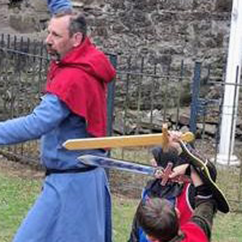 Two men yield swords dressed in blue and red medieval costumes.